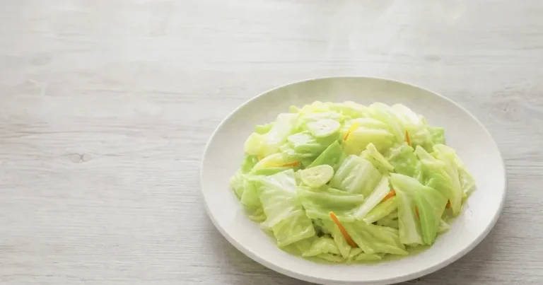 Taiwanese stir-fried cabbage on a white plate with garlic slices and carrot strips